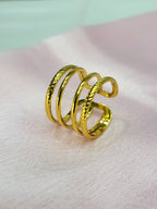 Lyvoria adjustable anti-tarnish gold plated stainless steel extra-wide cage ring featuring a four-row design with alternating twisted rope and smooth wires on a soft pink background.