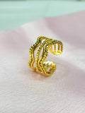 Estelle adjustable anti-tarnish gold plated stainless steel wide cage ring featuring a multi-row wave design with alternating smooth and beaded gold rows on a soft pink background.
