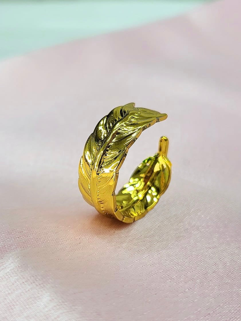 Novelle adjustable anti-tarnish gold plated stainless steel feather wrap ring showcasing intricate textured detailing on a soft pink satin background.